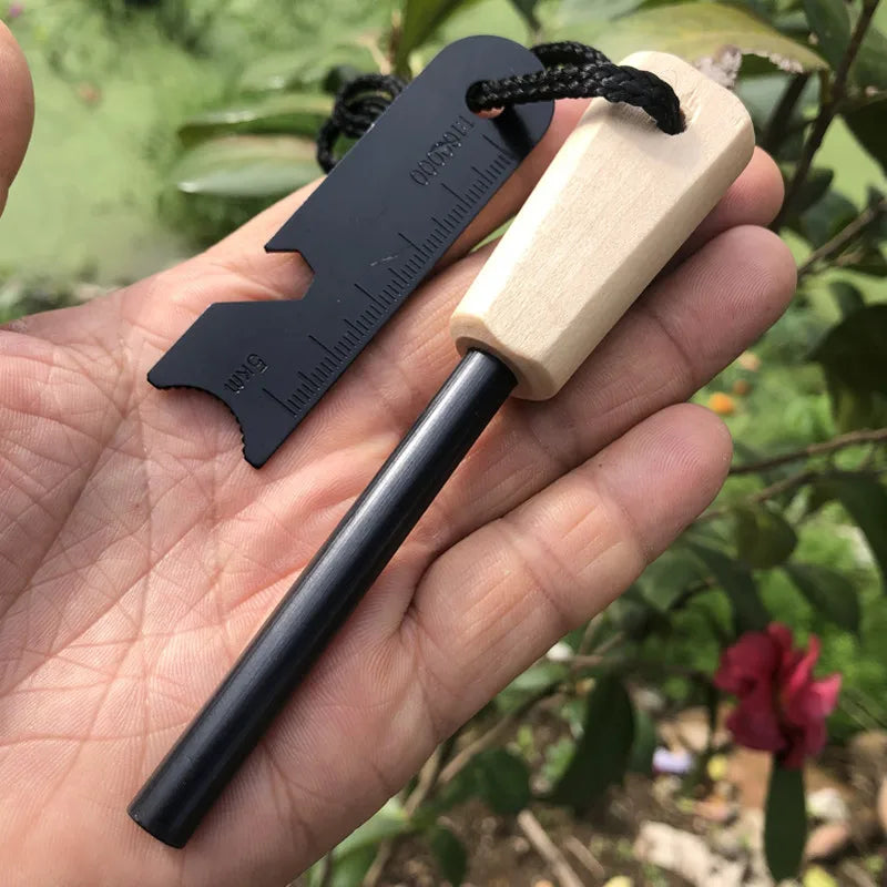 Fire starter tool with wooden handle and black metal head held in a hand against a natural background.